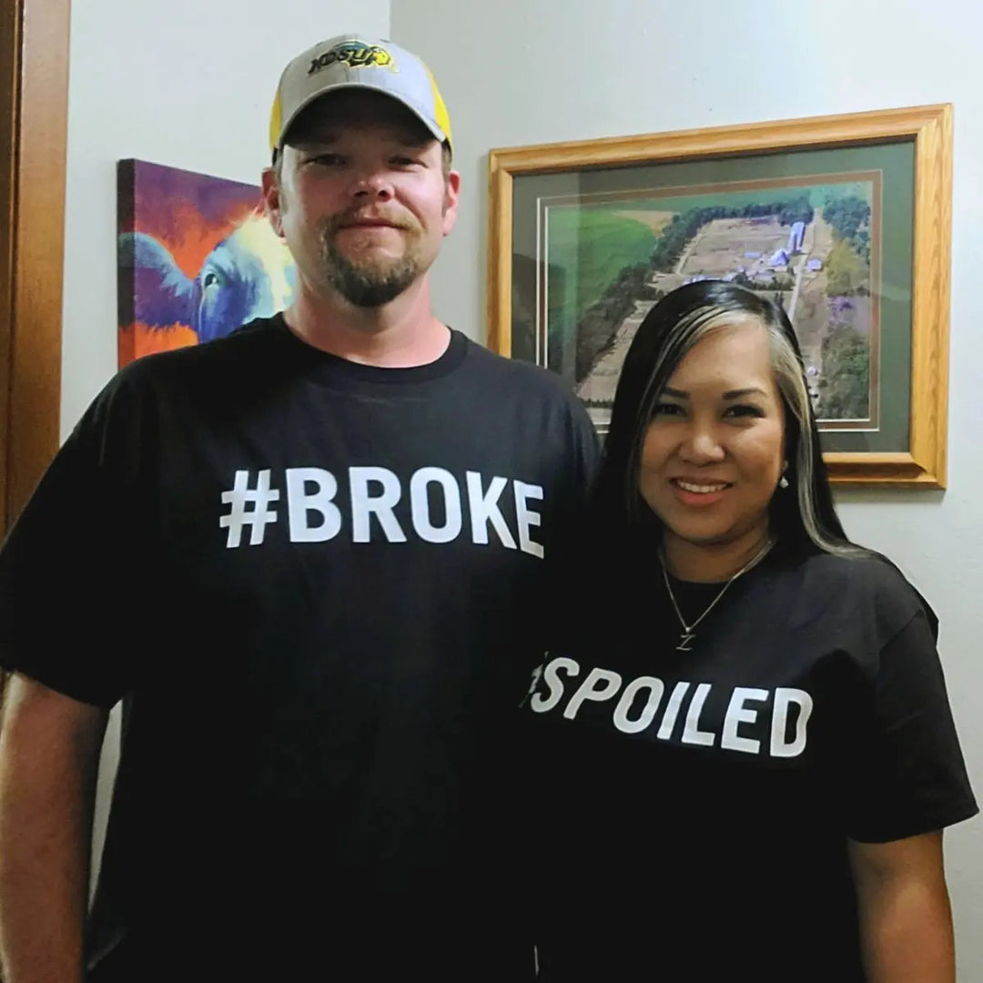 Couples' black matching tees—his says '#Broke', hers reads '#Spoiled' in bold white text. A hilarious and relatable duo for couples who know love isn’t always 50/50. From CouplesChoices.com.