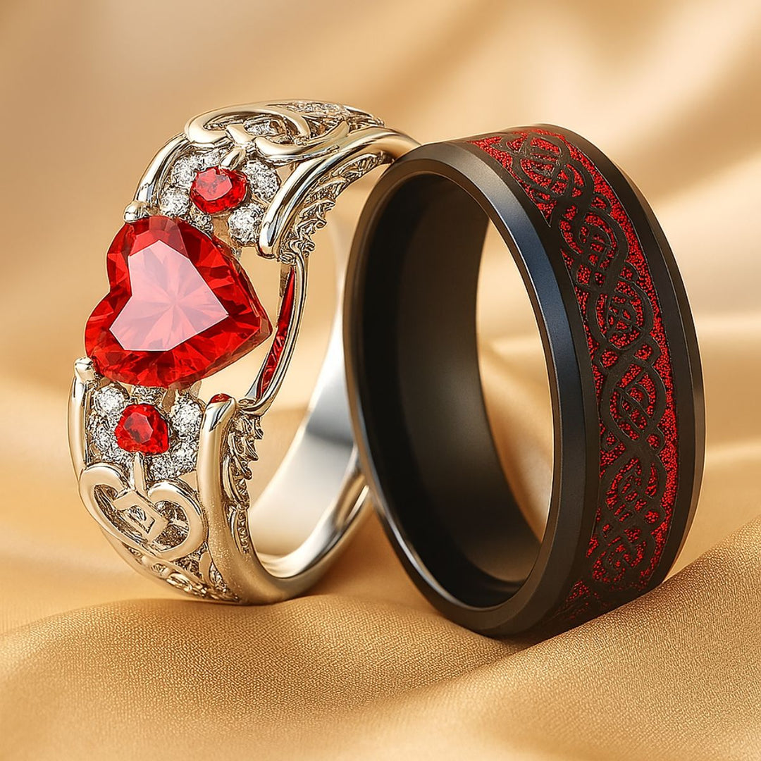 Cupid Arrow ring set from CouplesChoices.com, featuring a heart-shaped red gemstone in a filigree pavé band, paired with a black tungsten ring etched in crimson Celtic knotwork—crafted for eternal love.
