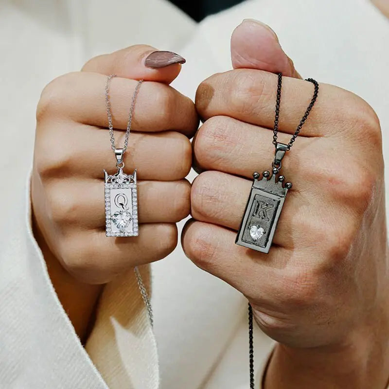 Matching King and Queen necklaces from CouplesChoices.com—black crown pendant with “K” for him and silver gem-framed pendant with “Q” for her. A bold, regal expression of love, loyalty, and royal couple energy.