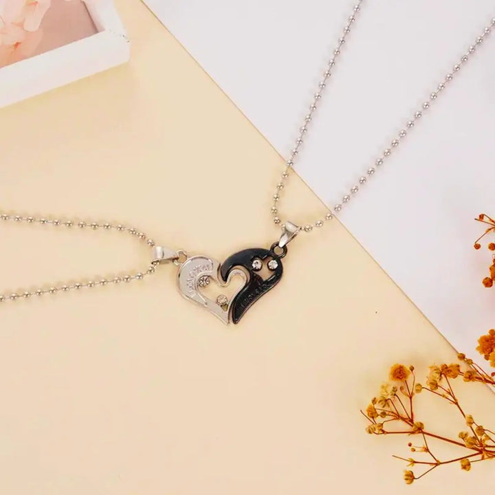 Matching couple necklaces from CouplesChoices.com featuring interlocking black and silver heart pendants engraved with “I Love You” and crystal accents—symbolizing unity, deep love, and everlasting connection.