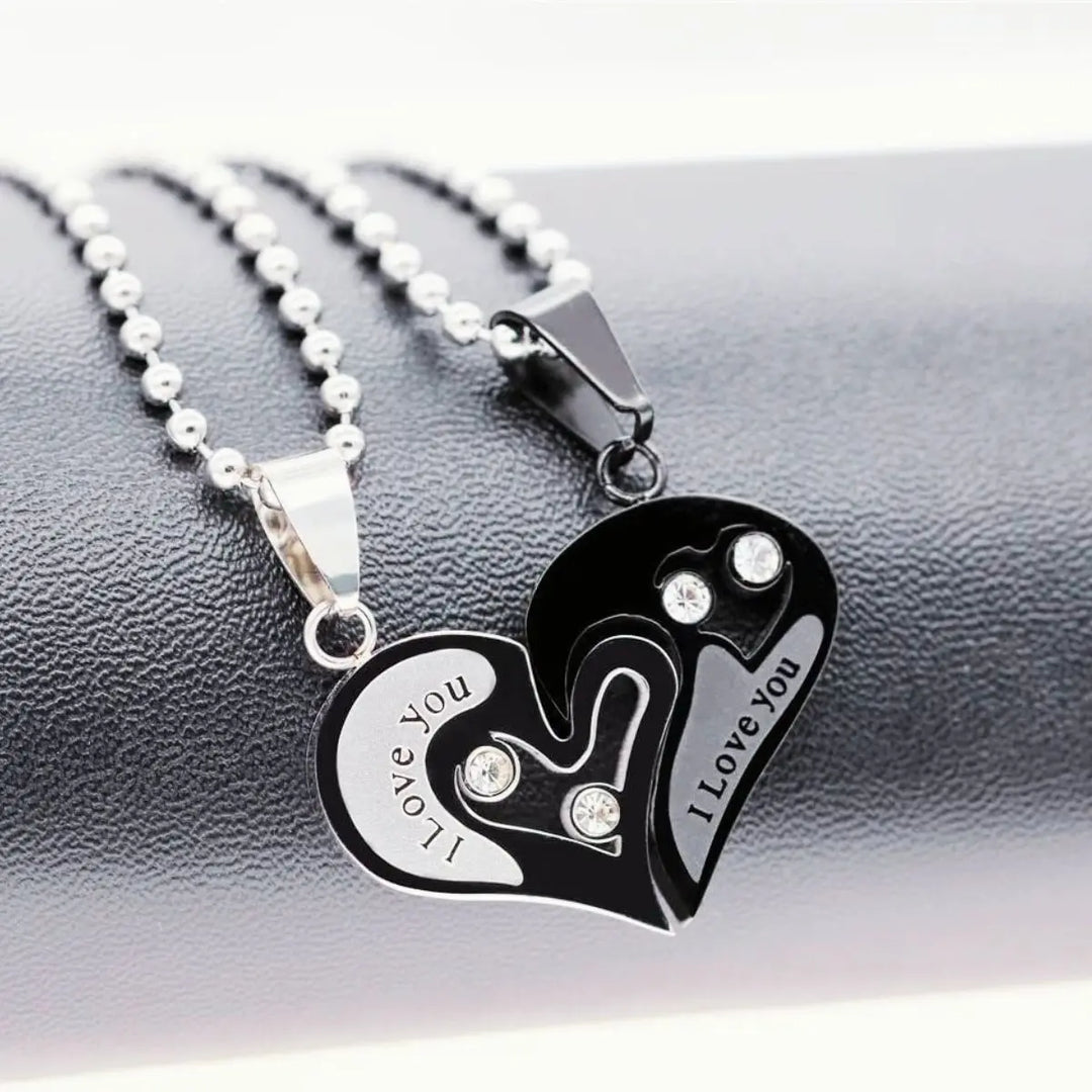 Matching couple necklaces from CouplesChoices.com featuring interlocking black and silver heart pendants engraved with “I Love You” and crystal accents—symbolizing unity, deep love, and everlasting connection.