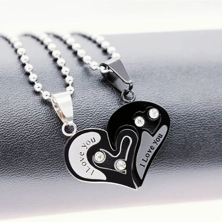 Matching couple necklaces from CouplesChoices.com featuring interlocking black and silver heart pendants engraved with “I Love You” and crystal accents—symbolizing unity, deep love, and everlasting connection.