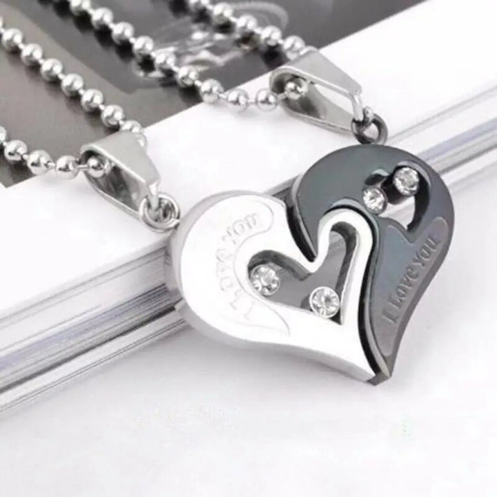 Matching couple necklaces from CouplesChoices.com featuring interlocking black and silver heart pendants engraved with “I Love You” and crystal accents—symbolizing unity, deep love, and everlasting connection.