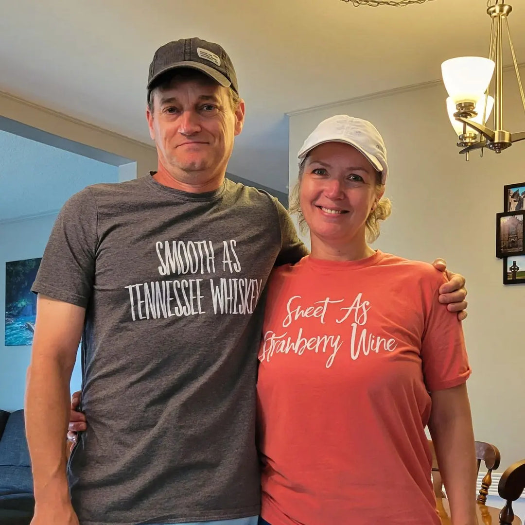 Matching couple shirts from CouplesChoices.com—his in charcoal gray reads “Smooth As Tennessee Whiskey,” hers in berry red says “Sweet As Strawberry Wine.” A stylish, country-inspired tribute to love, flavor, and southern charm.