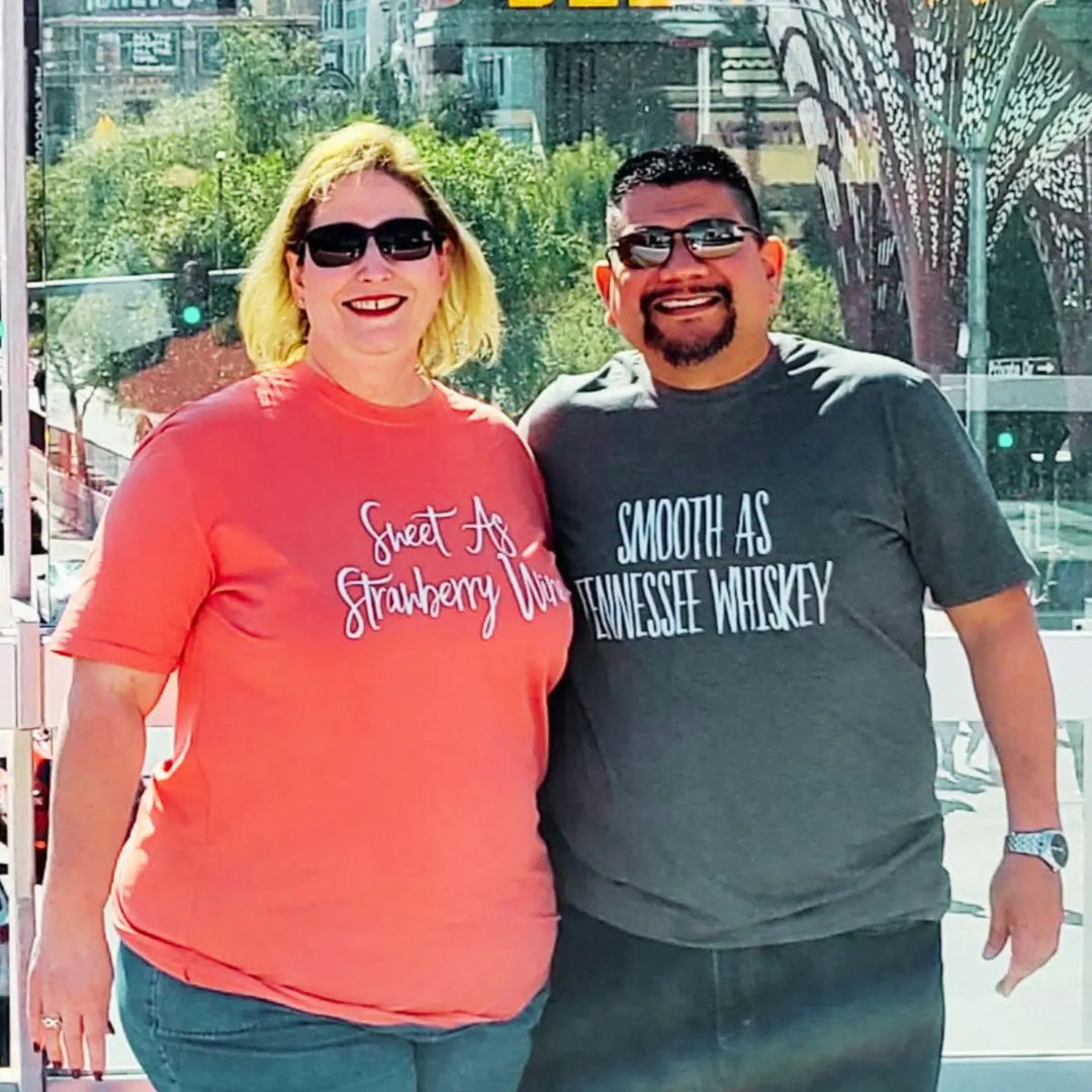 Matching couple shirts from CouplesChoices.com—his in charcoal gray reads “Smooth As Tennessee Whiskey,” hers in berry red says “Sweet As Strawberry Wine.” A stylish, country-inspired tribute to love, flavor, and southern charm.