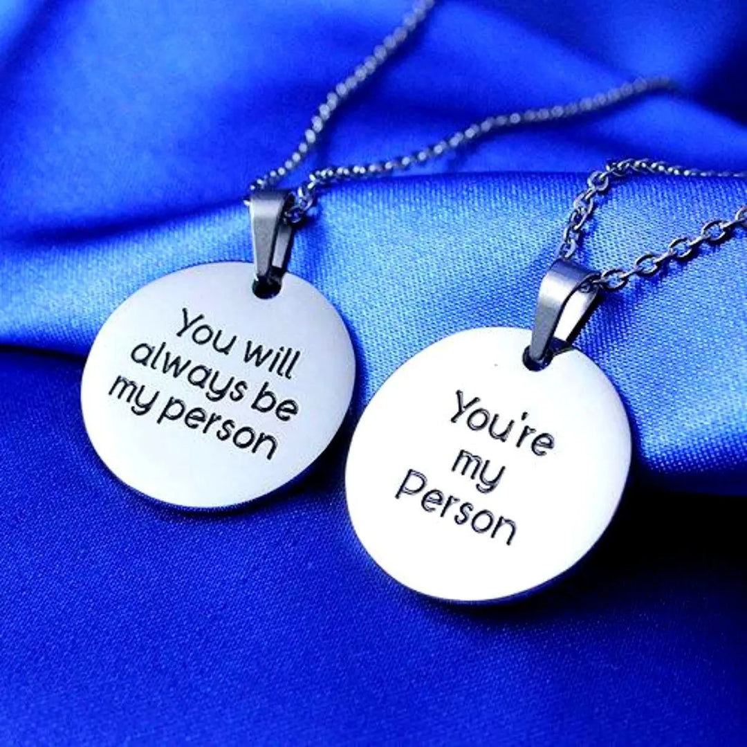 CouplesChoices.com matching stainless steel round pendant necklaces—one engraved with “You will always be my person,” the other with “You’re my person.” A heartfelt symbol of deep love, trust, and lasting emotional connection.