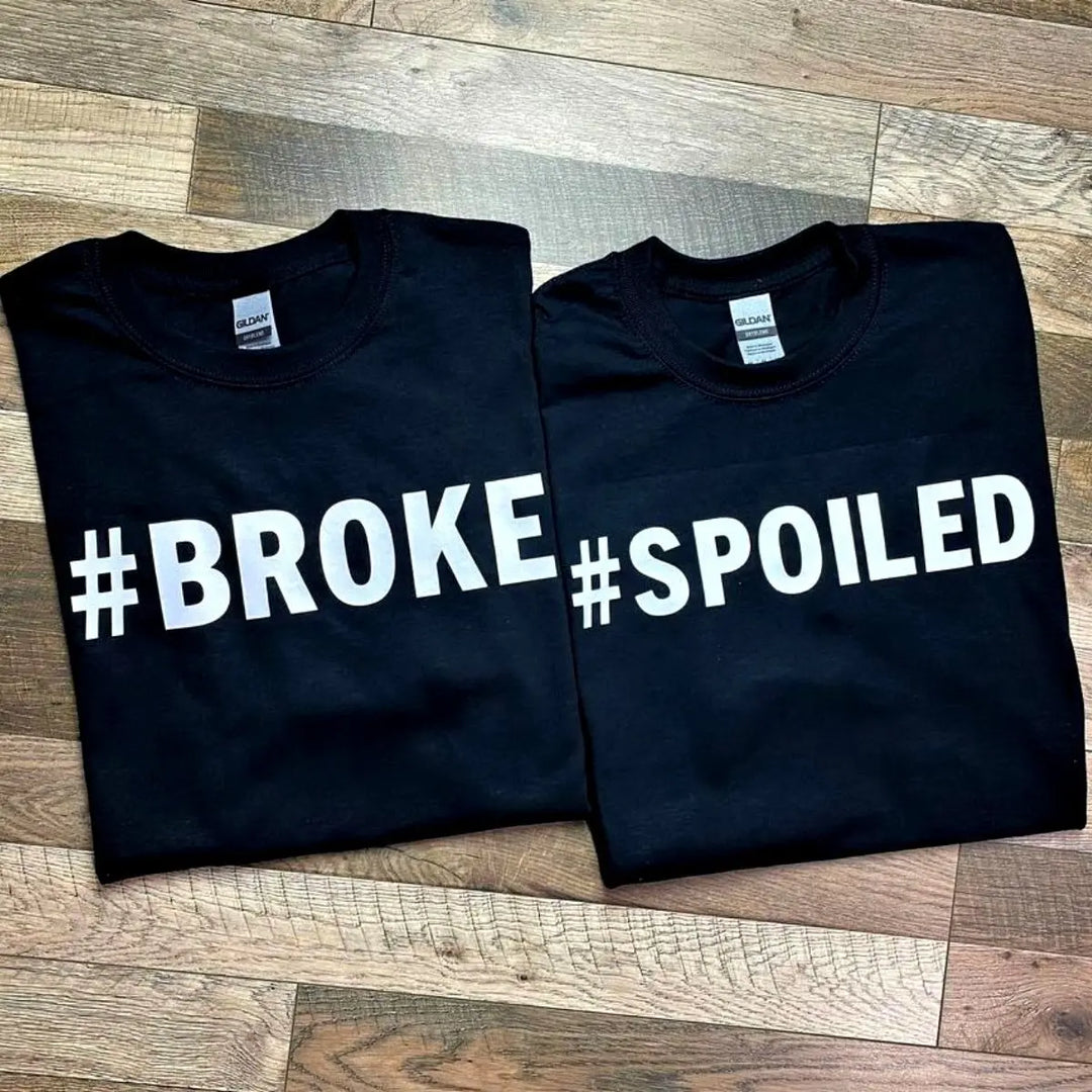 Couples' black matching tees—his says '#Broke', hers reads '#Spoiled' in bold white text. A hilarious and relatable duo for couples who know love isn’t always 50/50. From CouplesChoices.com.