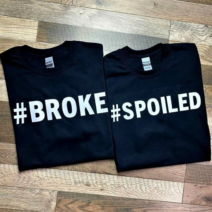 Couples' black matching tees—his says '#Broke', hers reads '#Spoiled' in bold white text. A hilarious and relatable duo for couples who know love isn’t always 50/50. From CouplesChoices.com.