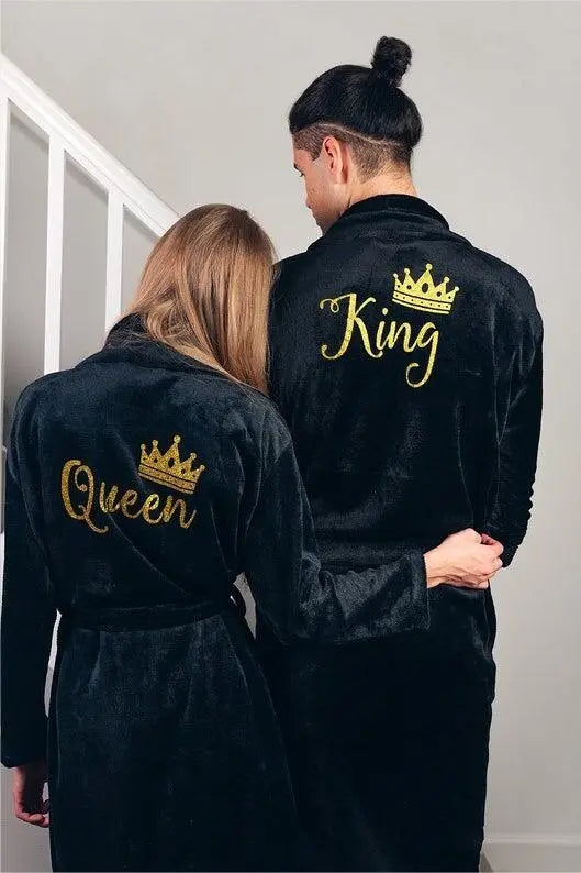 Elegant black his-and-hers bathrobes from CouplesChoices.com, featuring gold embroidered “King” and “Queen” lettering with royal crown accents—luxurious, coordinated loungewear designed to celebrate love, royalty, and refined comfort.