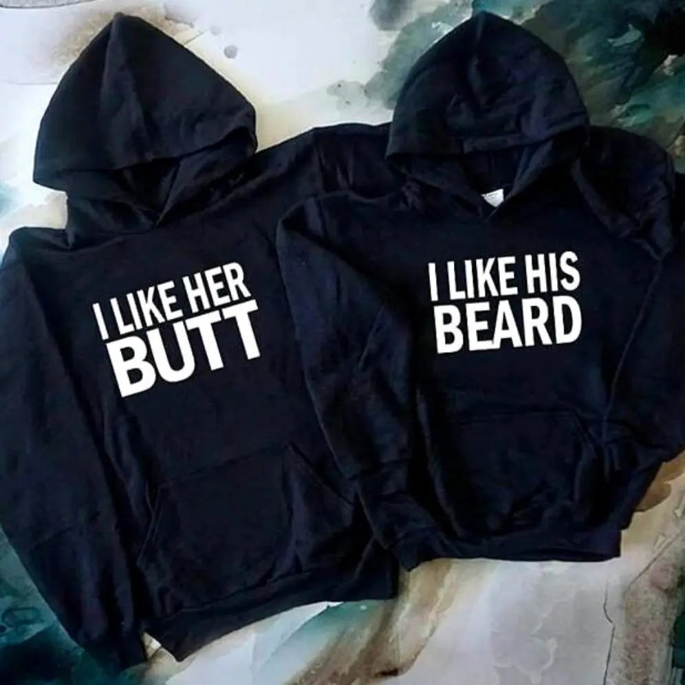 Matching black couple hoodies with bold white text — “I LIKE HER BUTT” on his and “I LIKE HIS BEARD” on hers — from CouplesChoices.com. Fun, flirty, and perfect for couples who love playful, stylish matching outfits.