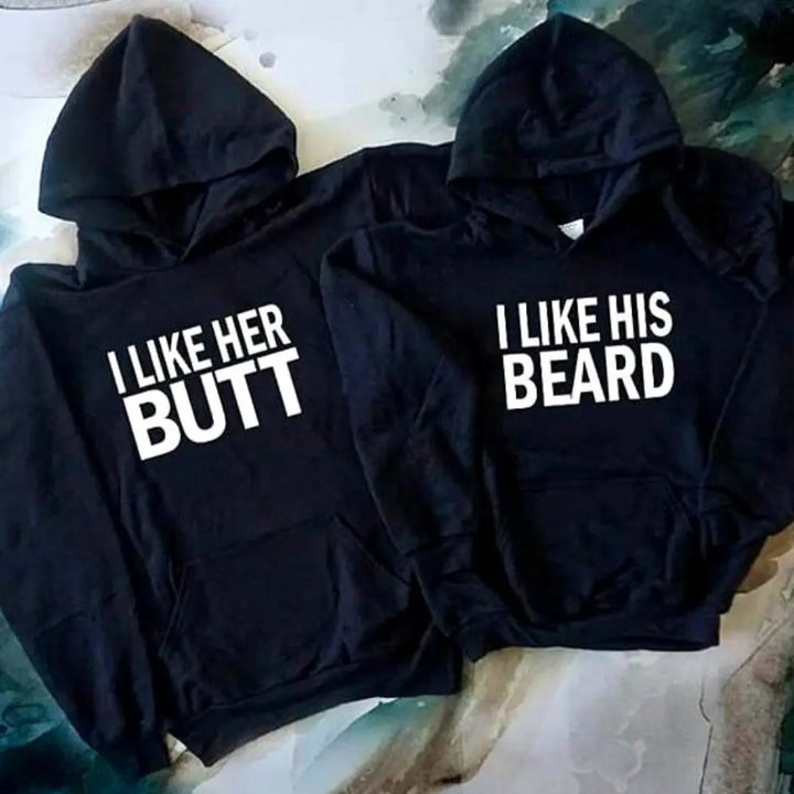 Matching black couple hoodies with bold white text — “I LIKE HER BUTT” on his and “I LIKE HIS BEARD” on hers — from CouplesChoices.com. Fun, flirty, and perfect for couples who love playful, stylish matching outfits.