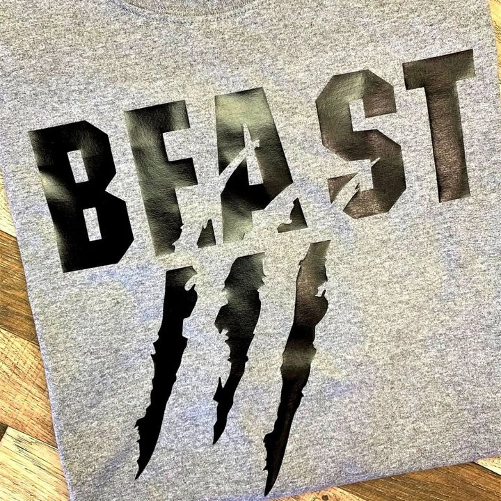 Matching grey couple shirts—his says 'Beast' with claw mark slashes, hers reads 'Beauty' with a bold lipstick kiss. A fierce-meets-flawless combo for couples from CouplesChoices.com.