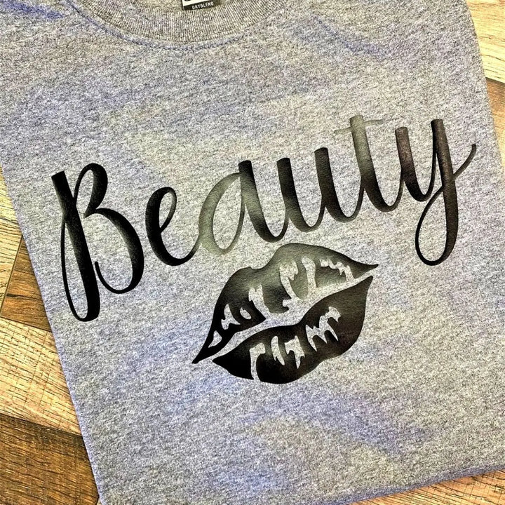 Matching grey couple shirts—his says 'Beast' with claw mark slashes, hers reads 'Beauty' with a bold lipstick kiss. A fierce-meets-flawless combo for couples from CouplesChoices.com.