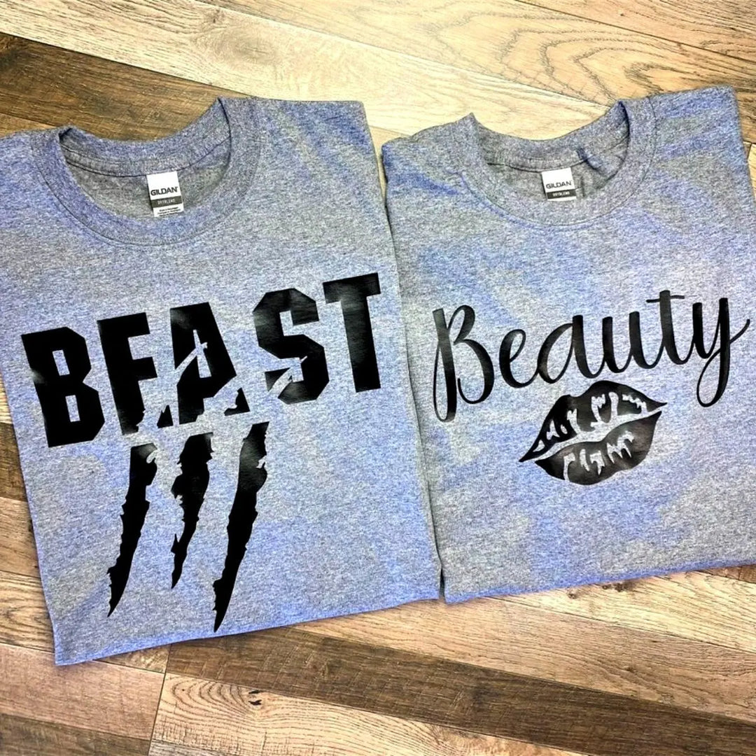 Matching grey couple shirts—his says 'Beast' with claw mark slashes, hers reads 'Beauty' with a bold lipstick kiss. A fierce-meets-flawless combo for couples from CouplesChoices.com.