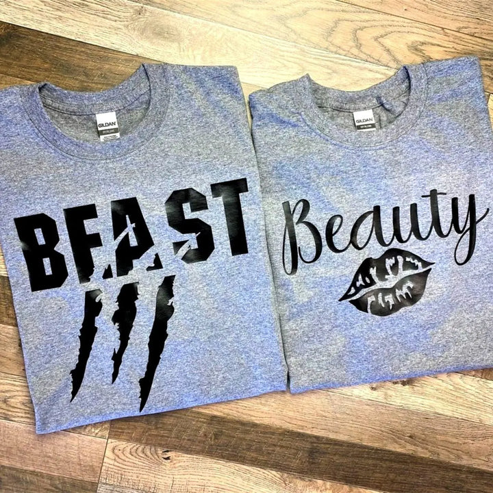 Matching grey couple shirts—his says 'Beast' with claw mark slashes, hers reads 'Beauty' with a bold lipstick kiss. A fierce-meets-flawless combo for couples from CouplesChoices.com.