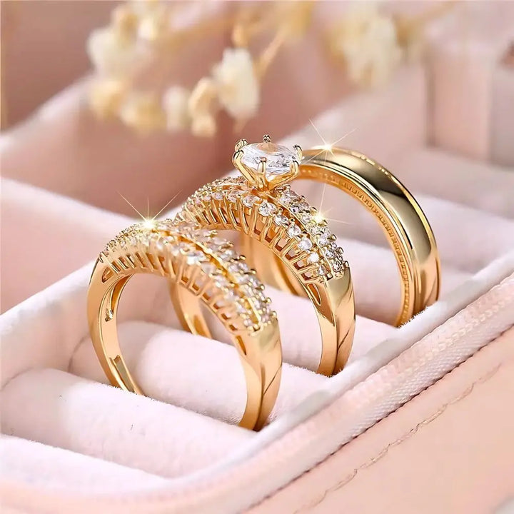 Allure Ring Set by CouplesChoices.com – a captivating 3-piece gold collection featuring a brilliant round-cut solitaire engagement ring, dual pavé-set eternity bands, and a sleek, polished men’s band. Crafted for timeless romance.