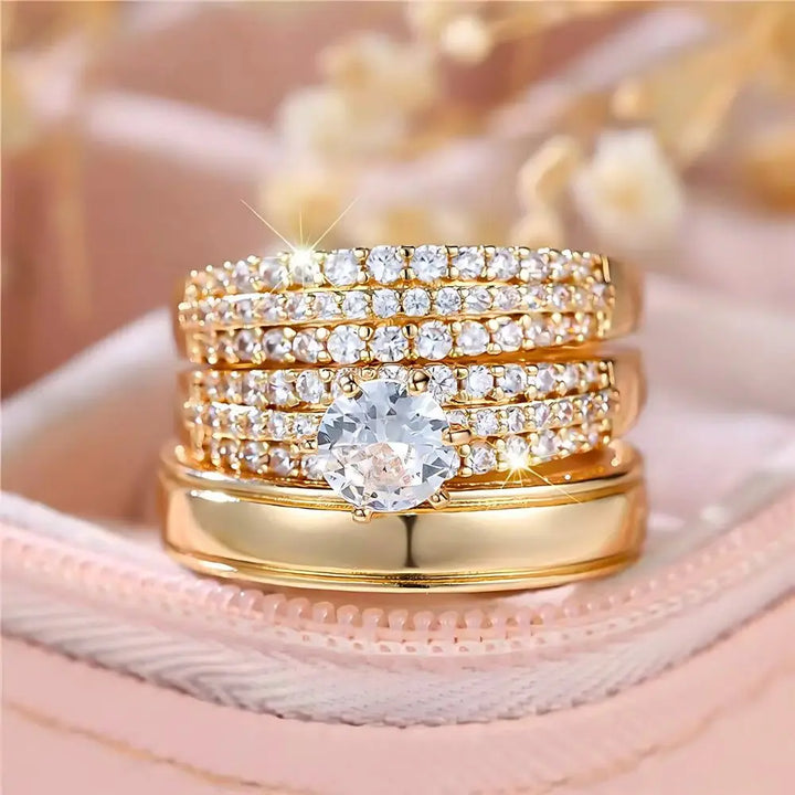 Allure Ring Set by CouplesChoices.com – a captivating 3-piece gold collection featuring a brilliant round-cut solitaire engagement ring, dual pavé-set eternity bands, and a sleek, polished men’s band. Crafted for timeless romance.