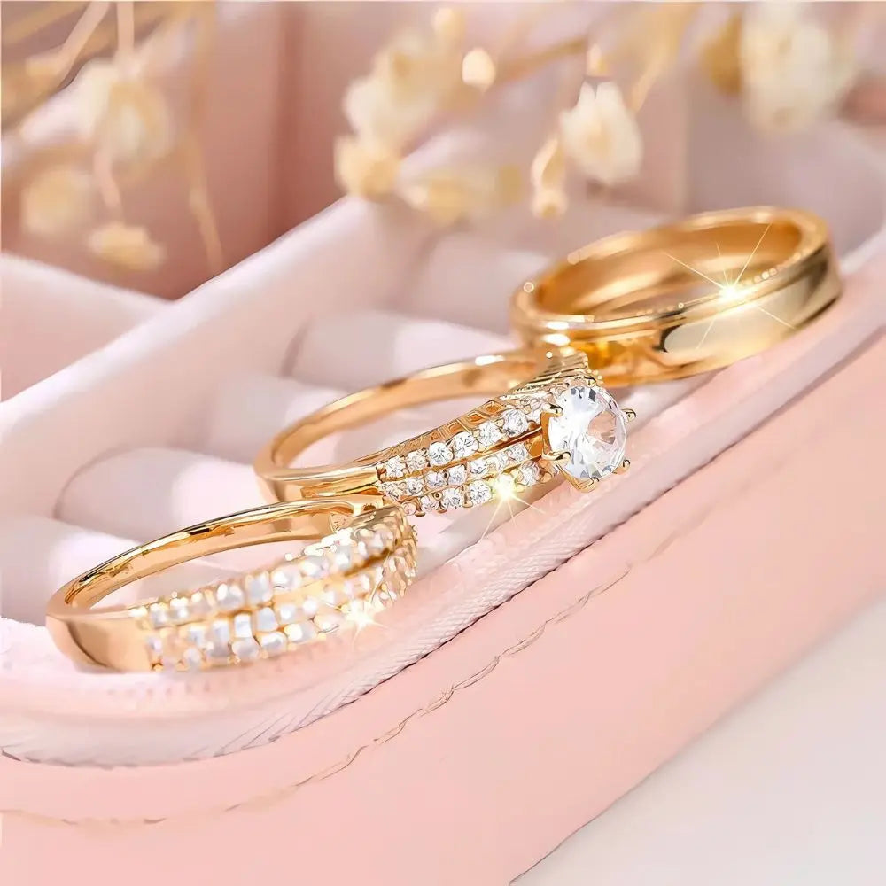 Allure Ring Set by CouplesChoices.com – a captivating 3-piece gold collection featuring a brilliant round-cut solitaire engagement ring, dual pavé-set eternity bands, and a sleek, polished men’s band. Crafted for timeless romance.