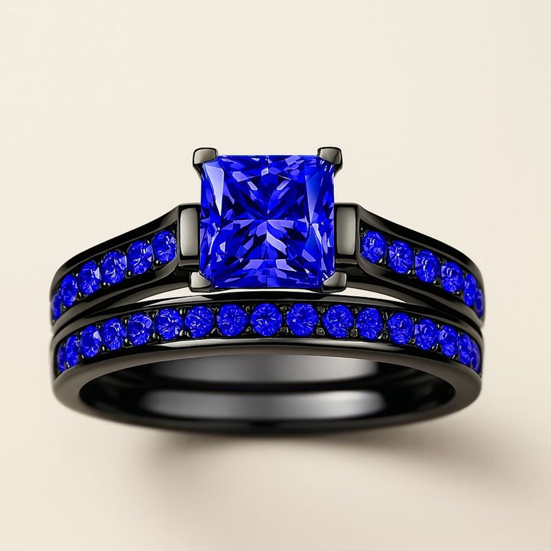 Blue Inspiration Ring Set by CouplesChoices.com featuring a radiant-cut sapphire-blue center stone on a sleek black band, flanked by pavé-set royal blue stones, paired with a matching eternity-style men’s band—crafted for bold connection.