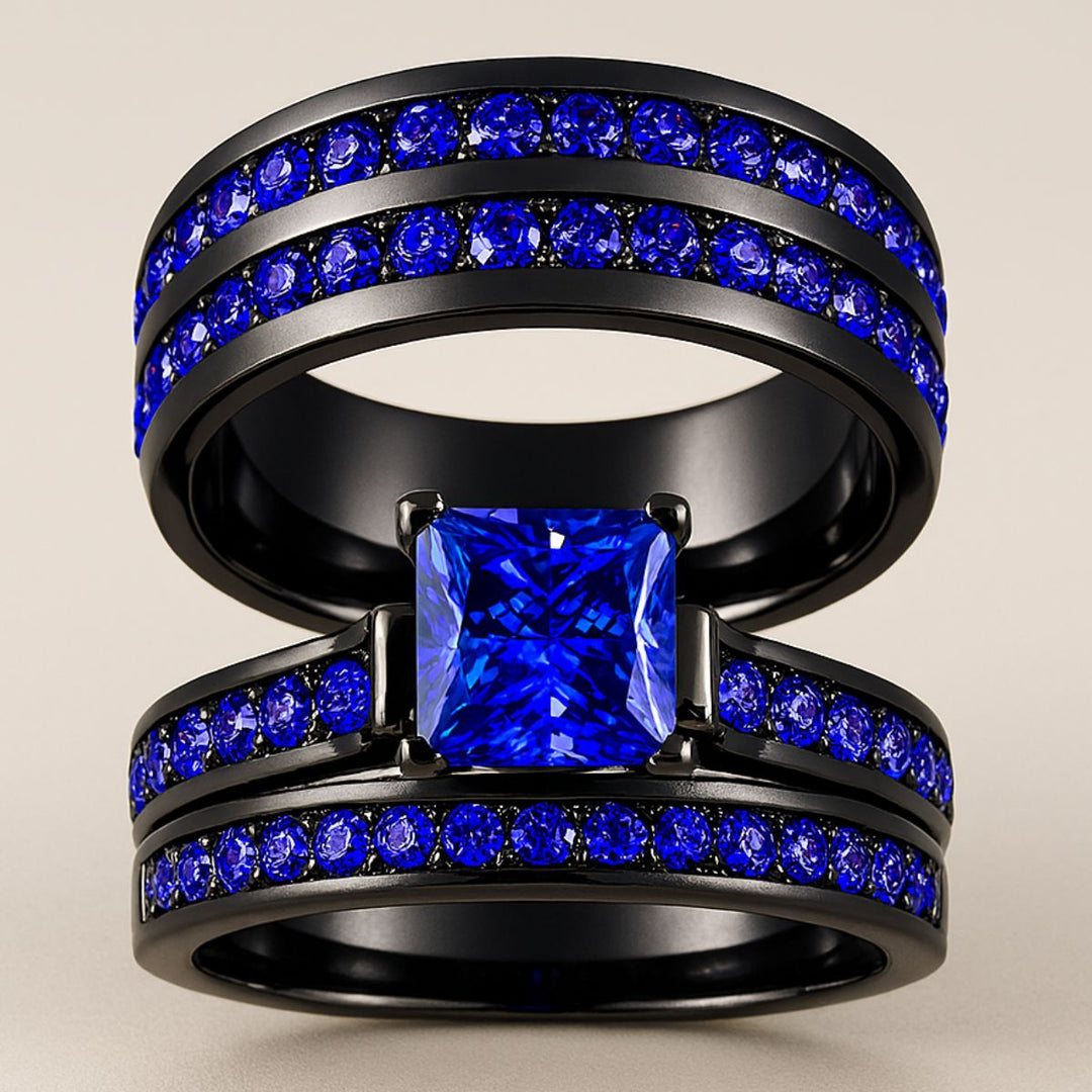 Blue Inspiration Ring Set by CouplesChoices.com featuring a radiant-cut sapphire-blue center stone on a sleek black band, flanked by pavé-set royal blue stones, paired with a matching eternity-style men’s band—crafted for bold connection.