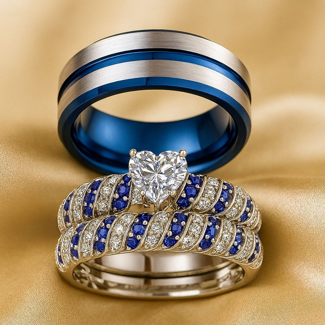 Blue Ocean wedding ring set from CouplesChoices.com, featuring a heart-shaped center stone flanked by pavé-set blue and white crystals in a twisted silver band, paired with a brushed silver and cobalt blue men's band.