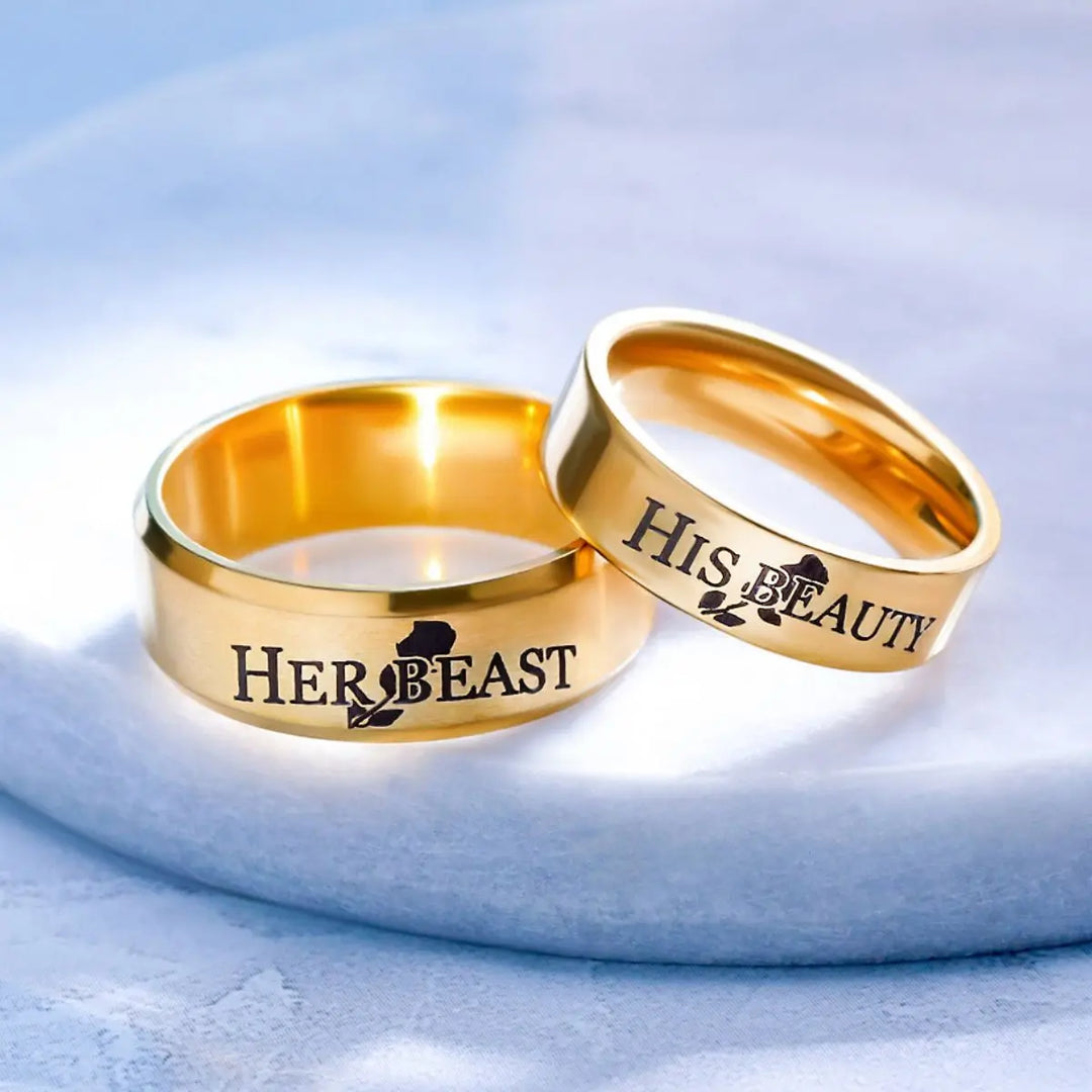 Celebrate timeless love with the Demure Rose Rings from CouplesChoices.com—gold bands engraved with “Her Beast” and “His Beauty,” symbolizing a powerful, elegant bond inspired by a tale as old as time.