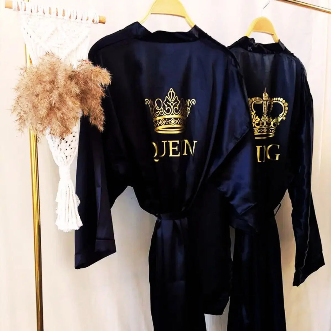 Chic satin black couple’s bathrobes from CouplesChoices.com, featuring regal gold “King” and “Queen” embroidery with intricate crown designs—elegant, lightweight loungewear crafted for style, comfort, and royal romance.