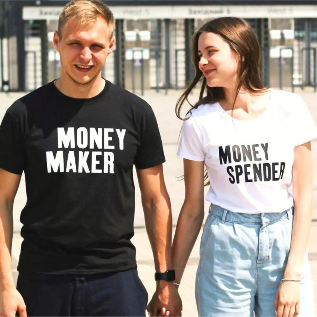 Couple shirts with bold contrast—black tee reads 'Money Maker' in white, white tee says 'Money Spender' in black. A fun power-pair look for couples who balance the books their way. From CouplesChoices.com.