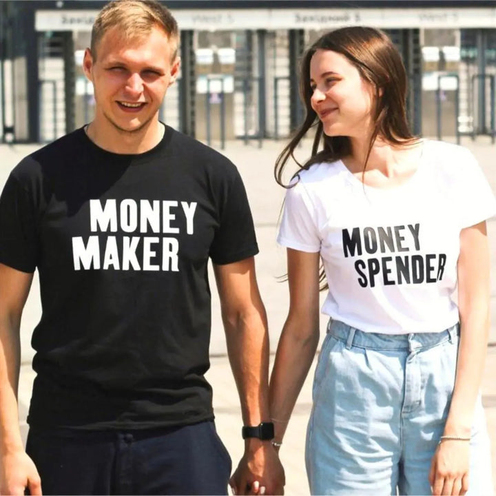 Couple shirts with bold contrast—black tee reads 'Money Maker' in white, white tee says 'Money Spender' in black. A fun power-pair look for couples who balance the books their way. From CouplesChoices.com.