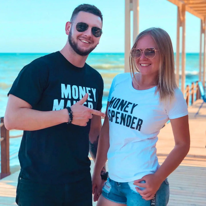 Couple shirts with bold contrast—black tee reads 'Money Maker' in white, white tee says 'Money Spender' in black. A fun power-pair look for couples who balance the books their way. From CouplesChoices.com.