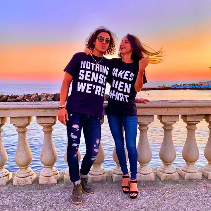 Couple wearing matching black shirts that read 'Nothing Makes Sense We’re' and 'Makes When Apart'—a playful and heartfelt message when worn together. Perfect for couples who want to show love and humor. From CouplesChoices.com.