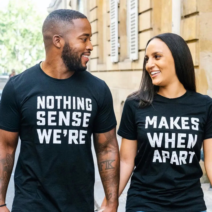 Couple wearing matching black shirts that read 'Nothing Makes Sense We’re' and 'Makes When Apart'—a playful and heartfelt message when worn together. Perfect for couples who want to show love and humor. From CouplesChoices.com.