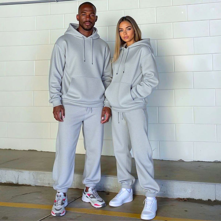 Couples confidently showcasing matching grey tracksuits from CouplesChoices.com, blending elevated comfort and minimalist style—ideal for modern loungewear or coordinated casual outings.