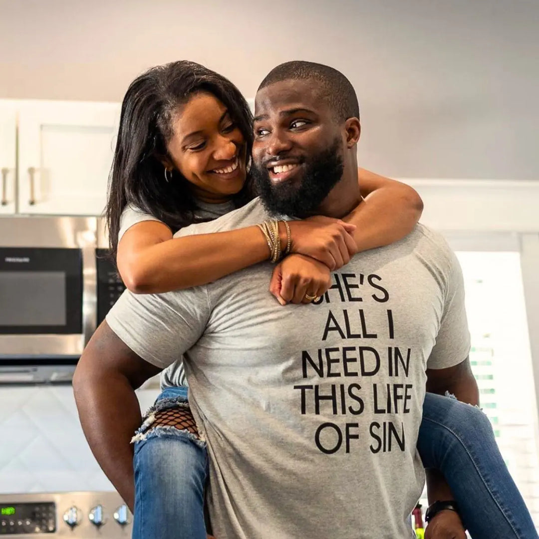 Couples’ matching grey tees with bold black text—his reads ‘She’s all I need in this life of sin,’ hers says ‘Down to ride til the very end.’ A fearless, ride-or-die statement set from CouplesChoices.com.