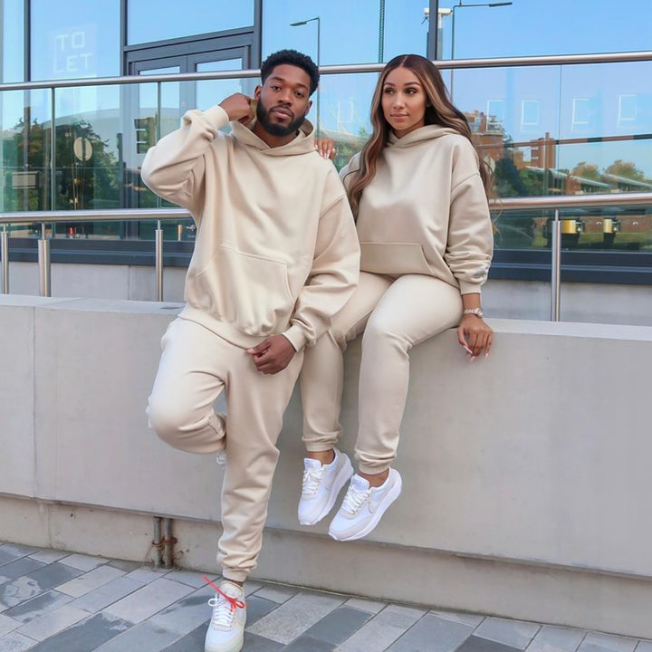 Couples wearing matching beige tracksuits from CouplesChoices.com, showcasing coordinated loungewear with a modern, minimalist design—perfect for casual outings or cozy indoor wear.