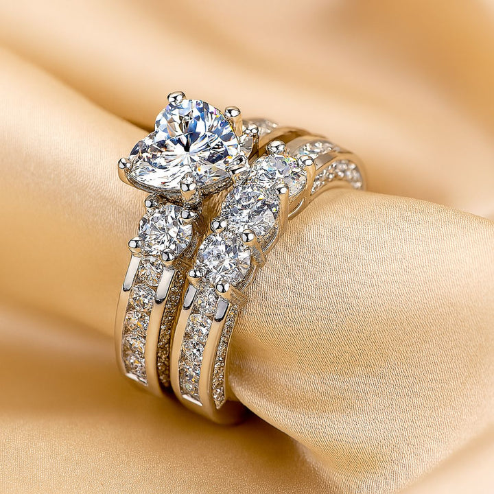 Elegant Hearted Love Rings by CouplesChoices.com, featuring a heart-shaped diamond centerpiece, triple-band pavé setting, and a matching diamond eternity men's band – luxury crafted for timeless commitment and bold style.