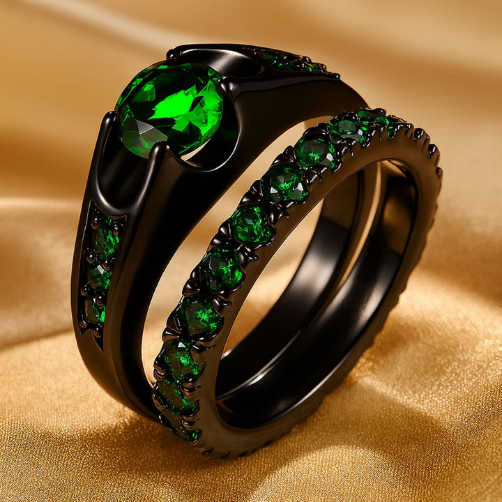 Emerald Love ring set by CouplesChoices.com, featuring a radiant green gemstone trio on black-plated bands and a matching men’s ring with shimmering emerald Celtic knotwork—bold, modern, eternal.