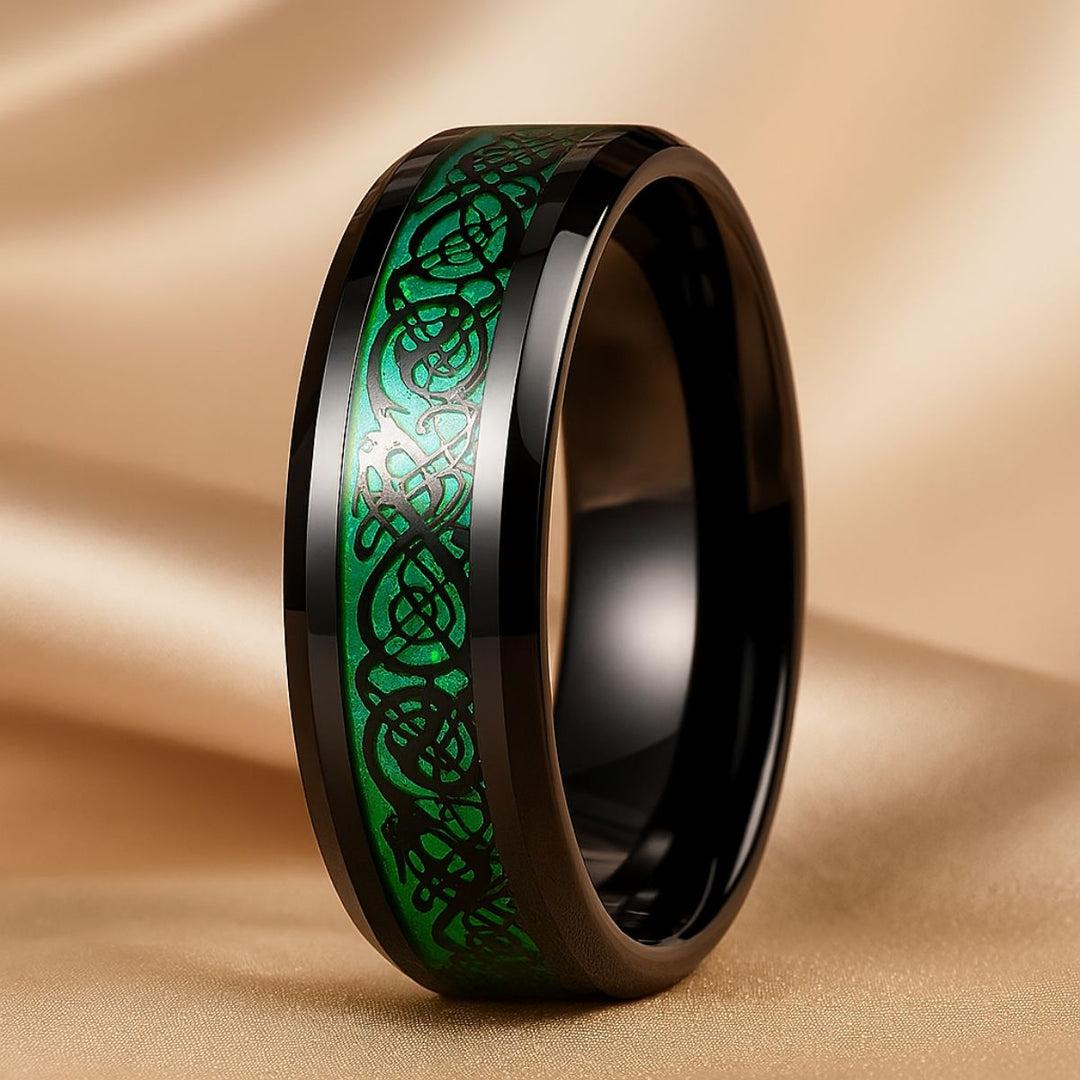 Emerald Love ring set by CouplesChoices.com, featuring a radiant green gemstone trio on black-plated bands and a matching men’s ring with shimmering emerald Celtic knotwork—bold, modern, eternal.