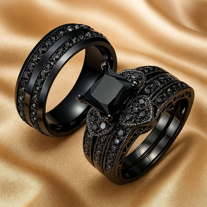 Love Glory Rings from CouplesChoices.com, featuring a bold princess-cut black diamond ring surrounded by pavé-set black stones and heart-shaped accents, paired with a matching dual-row black diamond band — a striking symbol of everlasting love.