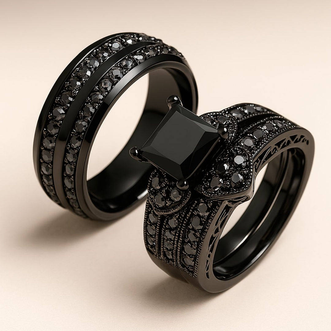 Love Glory Rings from CouplesChoices.com, featuring a bold princess-cut black diamond ring surrounded by pavé-set black stones and heart-shaped accents, paired with a matching dual-row black diamond band — a striking symbol of everlasting love.