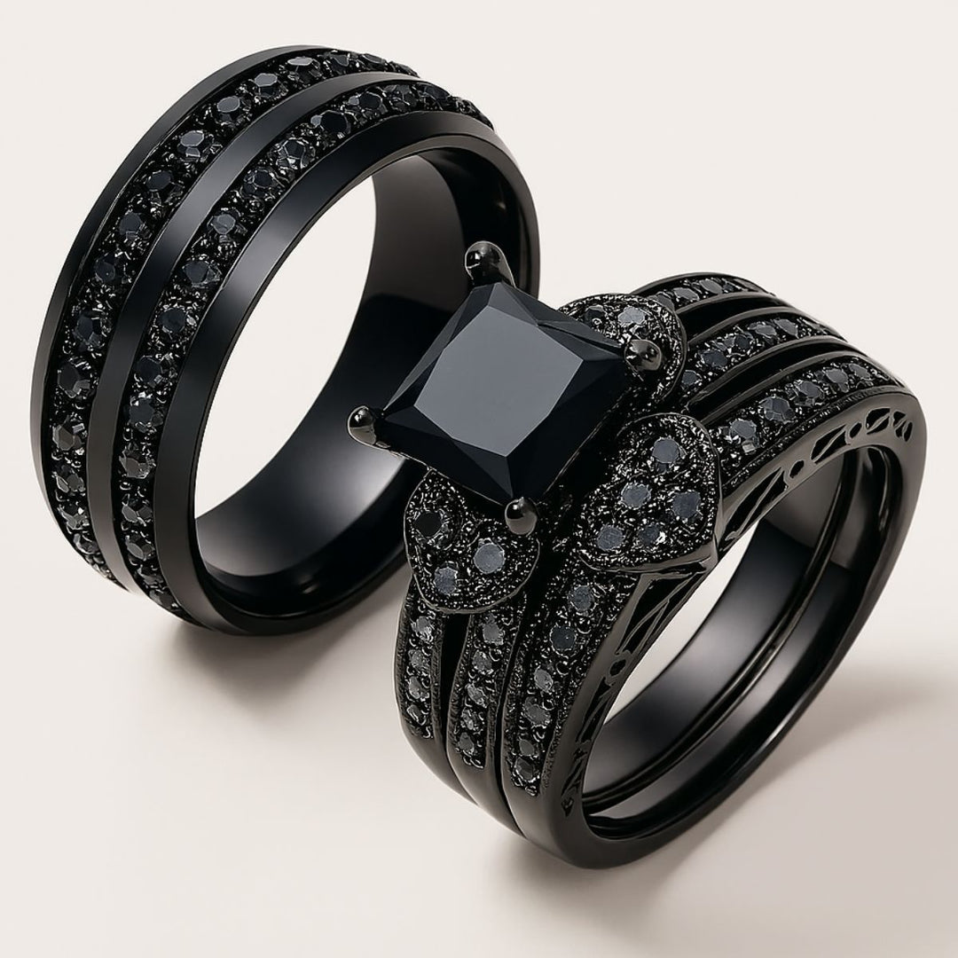 Love Glory Rings from CouplesChoices.com, featuring a bold princess-cut black diamond ring surrounded by pavé-set black stones and heart-shaped accents, paired with a matching dual-row black diamond band — a striking symbol of everlasting love.