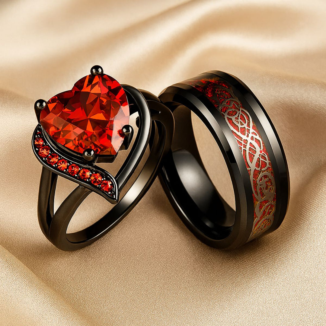 Love Story Ring Set by CouplesChoices.com showcasing a heart-shaped red gemstone on a black gold split-shank ring with red pavé accents, paired with a black men’s band featuring engraved Celtic motifs in red—crafted to symbolize bold love.