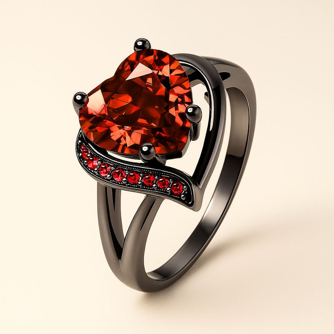 Love Story Ring Set by CouplesChoices.com showcasing a heart-shaped red gemstone on a black gold split-shank ring with red pavé accents, paired with a black men’s band featuring engraved Celtic motifs in red—crafted to symbolize bold love.