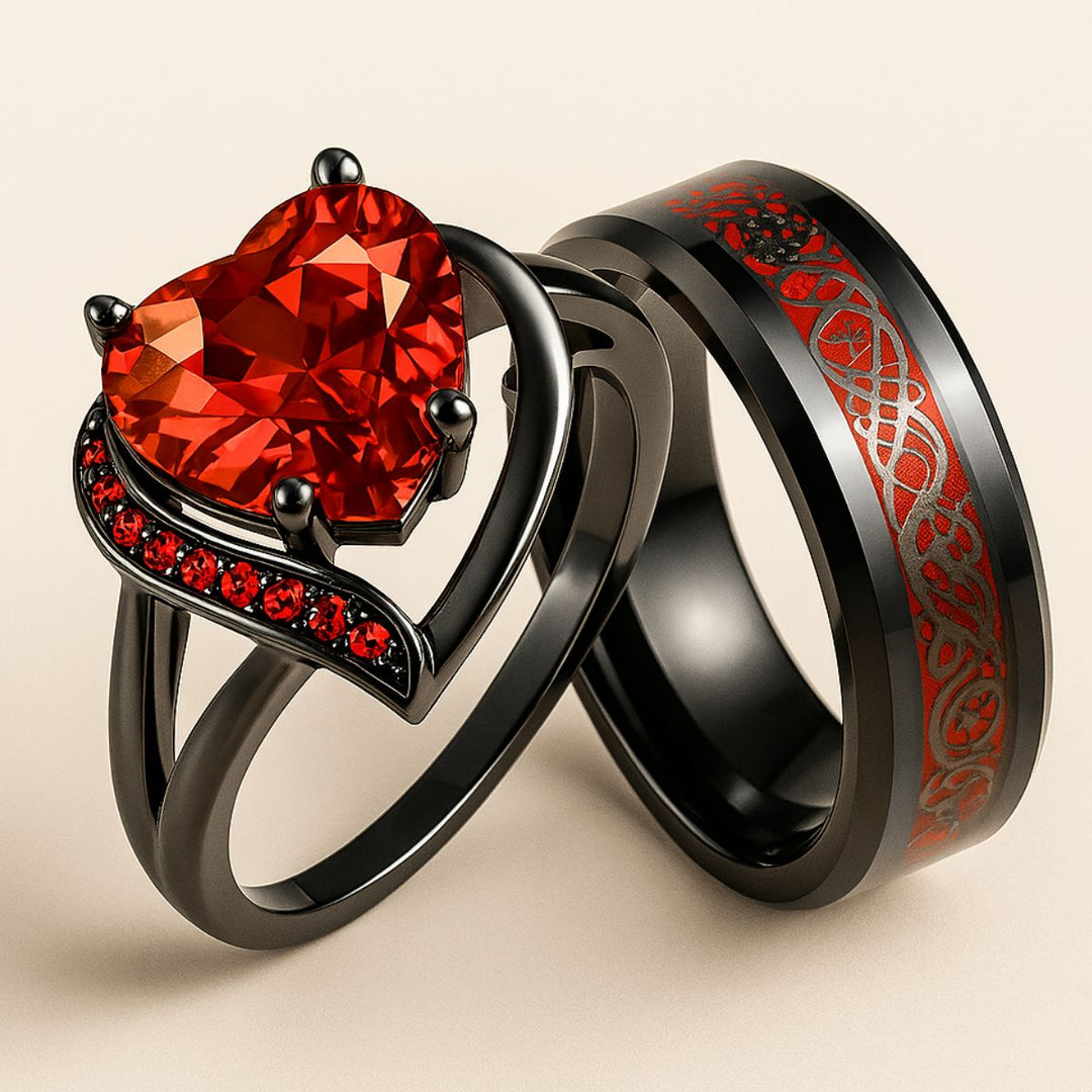 Love Story Ring Set by CouplesChoices.com showcasing a heart-shaped red gemstone on a black gold split-shank ring with red pavé accents, paired with a black men’s band featuring engraved Celtic motifs in red—crafted to symbolize bold love.