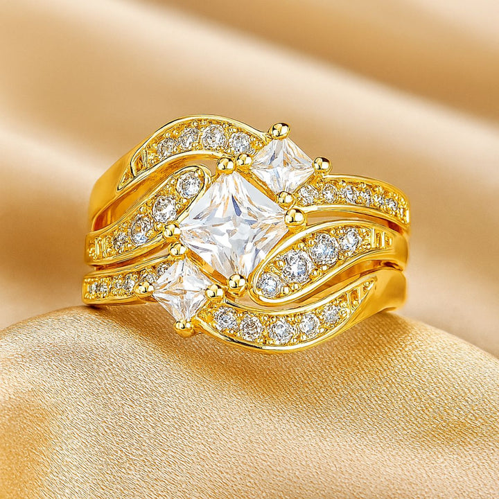 Lovely Ring Set by CouplesChoices.com featuring a gold-plated bridal trio with a radiant princess-cut center stone, flowing pavé-accented bands, and a textured two-tone men’s ring—crafted to embody elegance, unity, and timeless love.