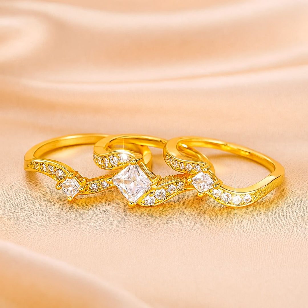 Lovely Ring Set by CouplesChoices.com featuring a gold-plated bridal trio with a radiant princess-cut center stone, flowing pavé-accented bands, and a textured two-tone men’s ring—crafted to embody elegance, unity, and timeless love.