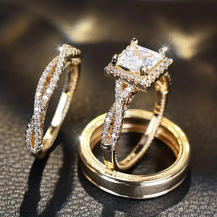 Lumina ring set by CouplesChoices.com, showcasing a princess-cut center stone on a pavé infinity band in radiant gold, paired with a matching gold men’s band for a timeless, luminous union.