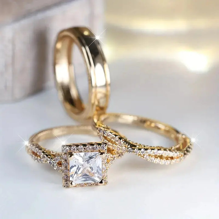 Lumina ring set by CouplesChoices.com, showcasing a princess-cut center stone on a pavé infinity band in radiant gold, paired with a matching gold men’s band for a timeless, luminous union.