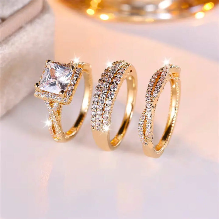 Luxurious 3-piece Euphoria Ring Set from CouplesChoices.com, showcasing a cushion-cut center stone on a pavé diamond gold band, paired with two matching eternity rings crafted for brilliance, elegance, and lasting romance.