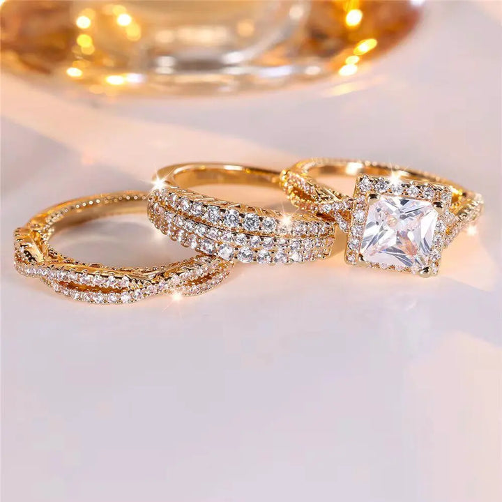 Luxurious 3-piece Euphoria Ring Set from CouplesChoices.com, showcasing a cushion-cut center stone on a pavé diamond gold band, paired with two matching eternity rings crafted for brilliance, elegance, and lasting romance.